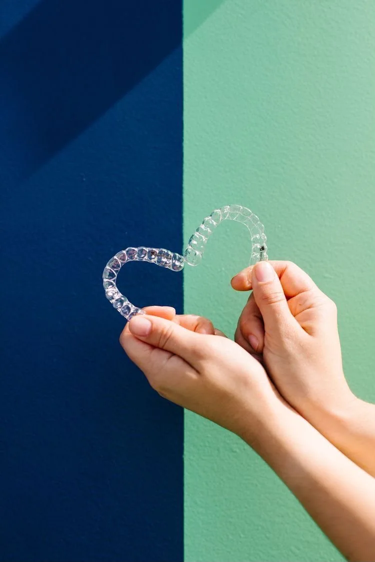 Hands holding two clear dental aligners