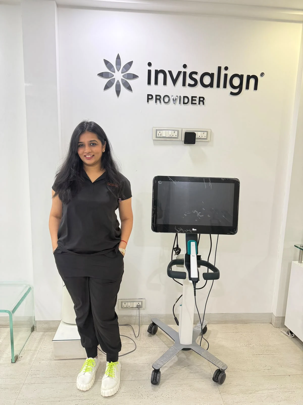 Dr. Feril Mehta beside the clinic iTero scanner under the Invisalign Provider sign